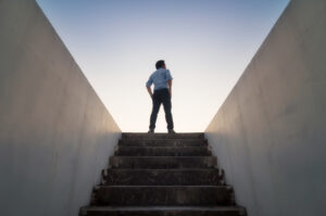 A professional standing on the top of the stairs representing career growth.