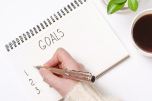 A hand writing on a notebook for her professional development goals.